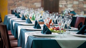 Una hilera de mesas dispuestas para un evento de cena formal, con manteles blancos y servilletas oscuras.