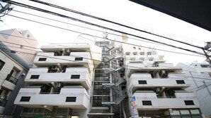 Un edificio residenziale a più piani con una scala centrale, posti auto e una macchina per distributore.