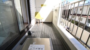 Un balcone con una sedia gialla, un paio di scarpe e un cartello a terra.