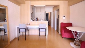 Una cucina moderna con isola centrale, due sedie, un tavolo da pranzo e un divano rosso.
