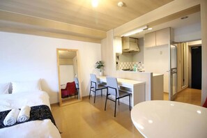 A hotel room with a bed, a desk, a chair, a small table, and a kitchen area. - F apt 202 Mickey House SHIBUYA SHINJUKU (Tokyo)