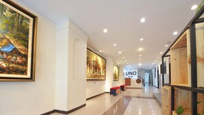 Un pasillo de hotel con obras de arte en las paredes, una zona de recepción y un cartel de UNO HOTEL.