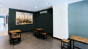 Una habitación con un cuadro grande, una puerta blanca y una zona de estar con mesas y sillas.