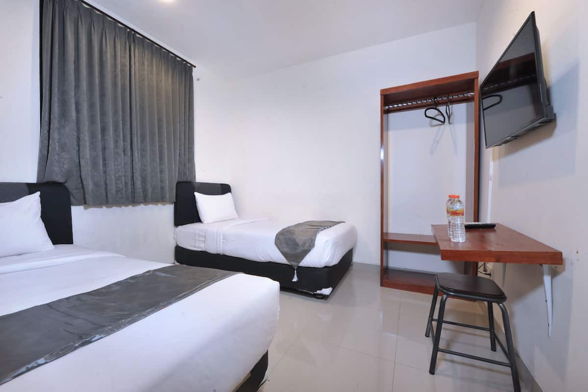 Una habitación de hotel con dos camas, un televisor montado en la pared, un escritorio de madera y un taburete.