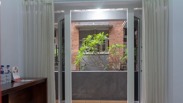 Una puerta abierta que da a un balcón con pared de ladrillo y una ventana.