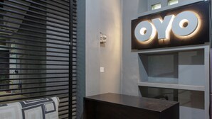 Un interior moderno con un letrero iluminado grande que dice "OYO" y un sofá estampado.