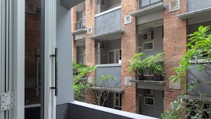 Un edificio residencial de varios pisos con fachadas de ladrillo, balcones y plantas en macetas.