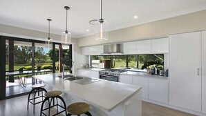 A modern kitchen with a large island, stainless steel appliances, and a view of the outdoors. - 1OAK - THE VINTAGE HOLIDAY HOUSES (POKOLBIN)