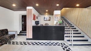 Una zona de recepción con un mostrador negro, una escalera y un suelo con diseño.