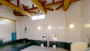 Un baño con vigas de madera, encimera de mármol, dos lavamanos y un espejo.