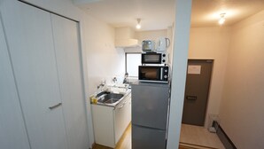 A compact kitchen with a sink, a microwave, and a small refrigerator. - Apartment Camon EBR0001E (Osaka)