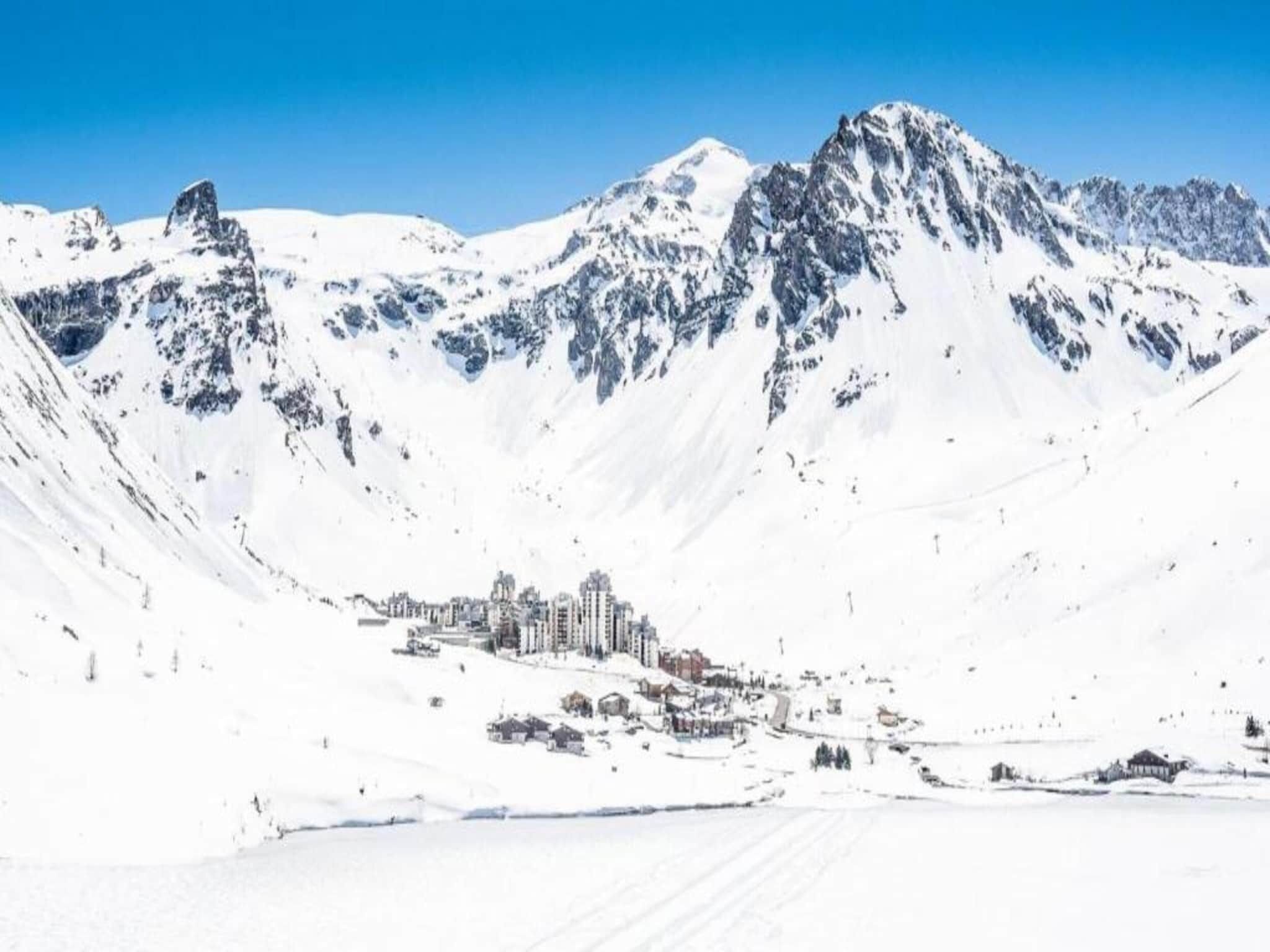 Een berglandschap met sneeuw, met een stadje aan de voet.