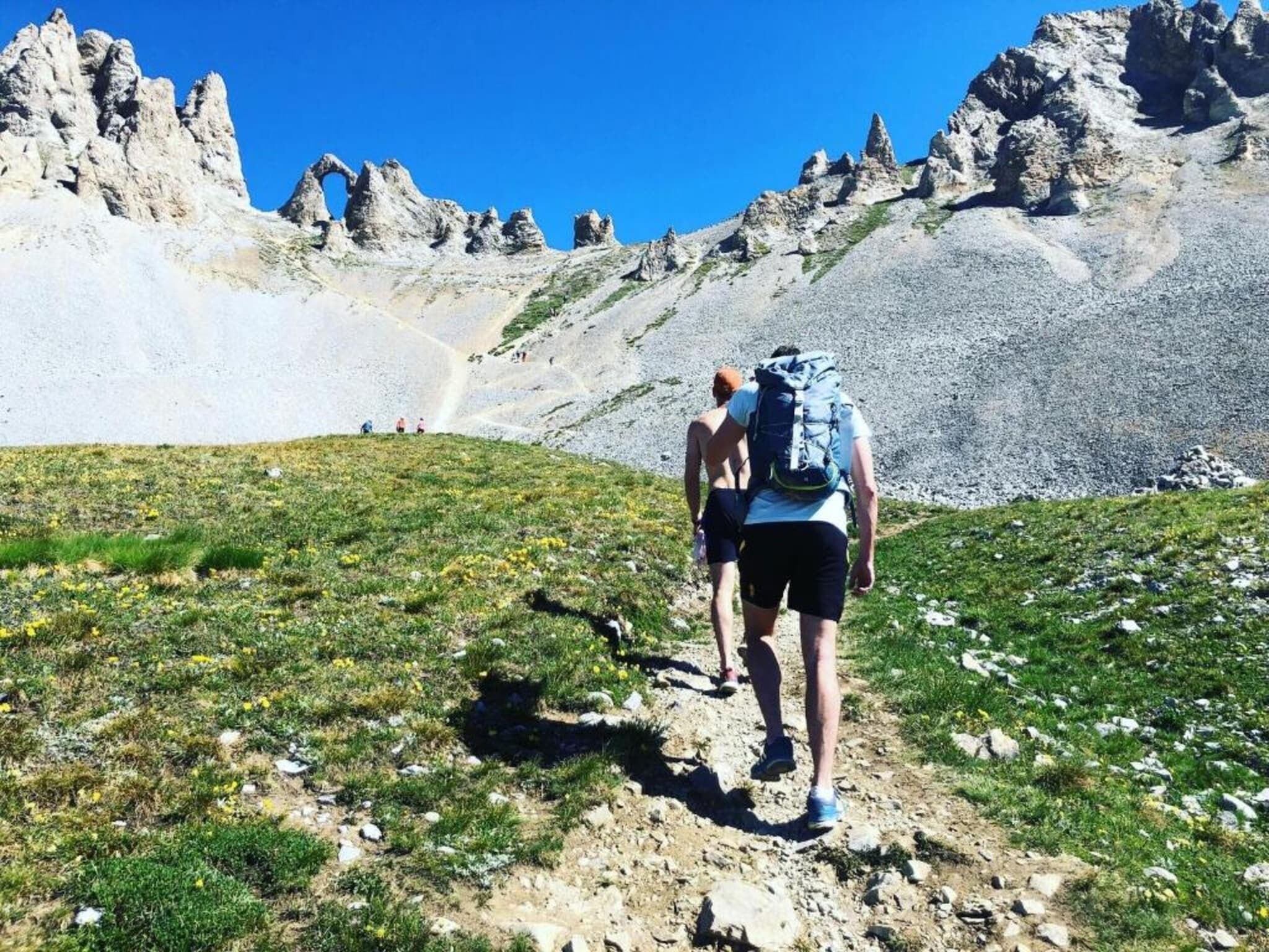 A hiking trail with rocky terrain and sparse vegetation, leading towards a mountainous landscape.
