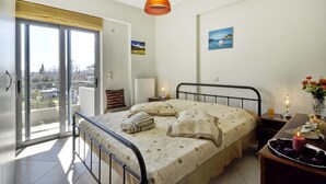 Un dormitorio con cama, mesita de noche, ventana y vistas a la ciudad.