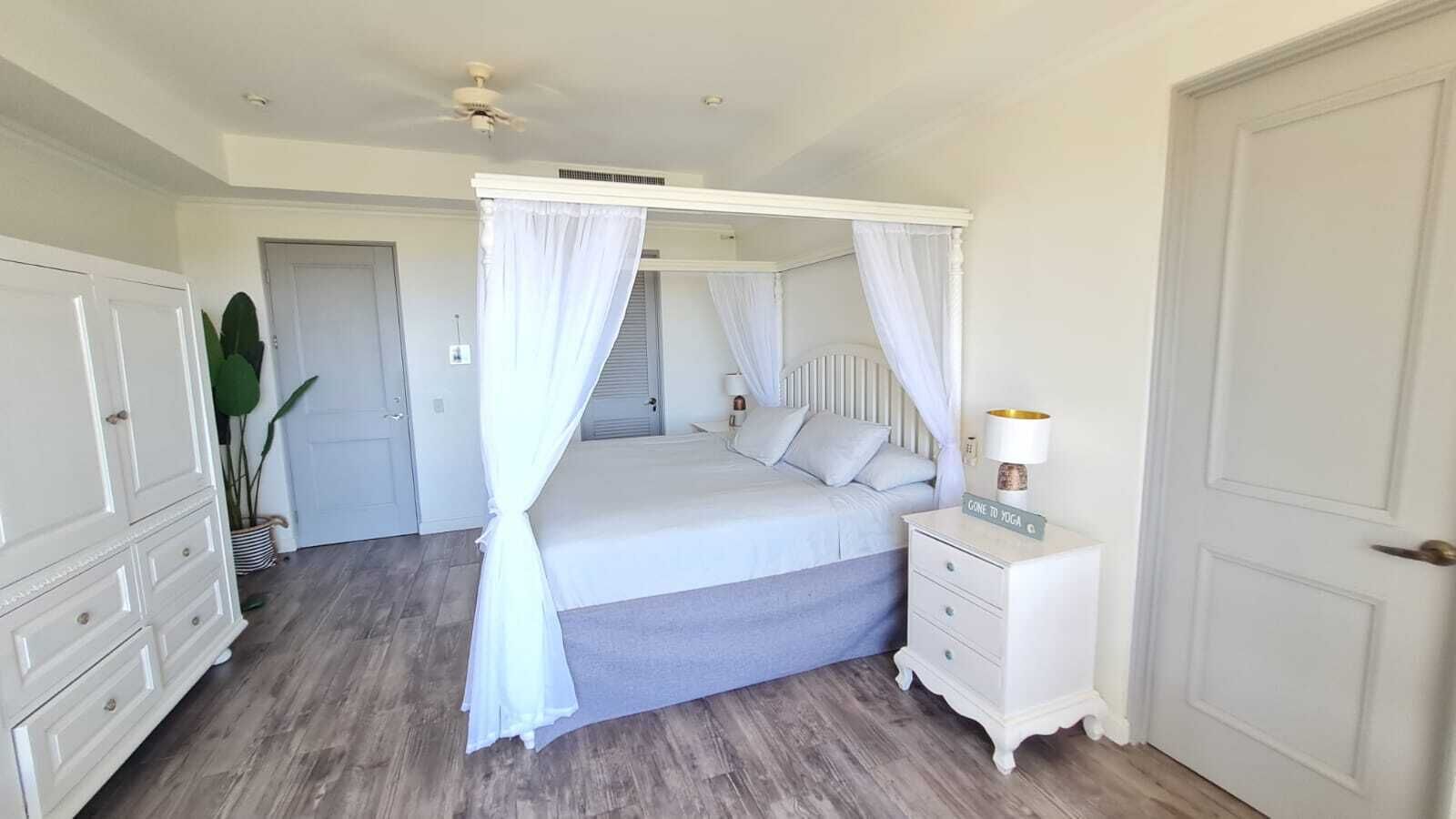 Un dormitorio con cama con dosel, una mesita de noche con lámpara y un armario.
