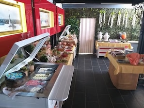 A buffet setup with various food items and a decorative wall with hanging plants. - Akcay Yavuz Otel (Edremit)