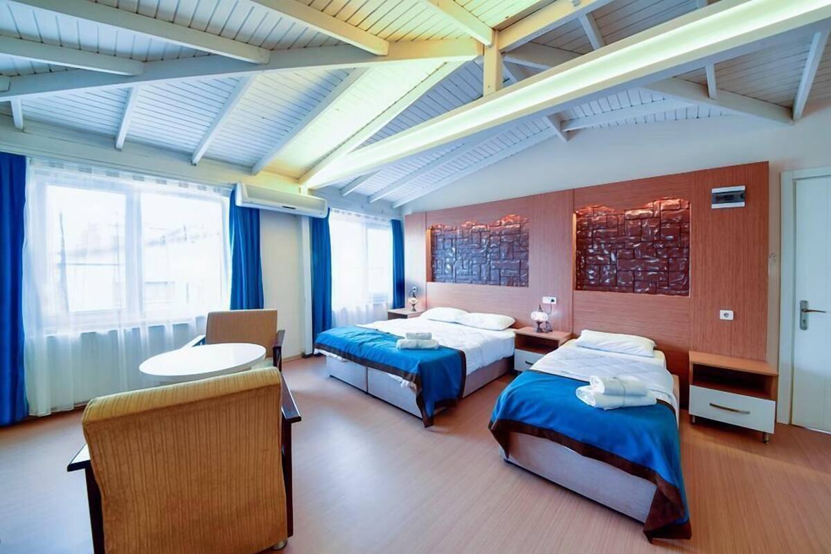 A hotel room with two beds, a round table, and a chair.