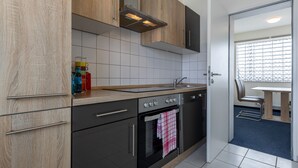 A modern kitchen with wooden cabinets, a stainless steel range, and a tiled backsplash. - Fly Inn Hotel Frankfurt Airport Rüsselsheim ehemals Trip Inn Hotels (Ruesselsheim)
