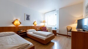 A hotel room with two beds, a desk, a chair, a television, and two lamps. - Fly Inn Hotel Frankfurt Airport Rüsselsheim ehemals Trip Inn Hotels (Ruesselsheim)