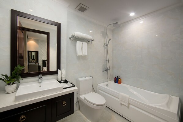 A modern bathroom with a white sink, toilet, and bathtub. There is a large mirror above the sink and a towel rack with towels.