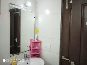 Ein Badezimmer mit einem weißen Waschbecken, einem rosa Zahnbürstenhalter und einem Spiegel.