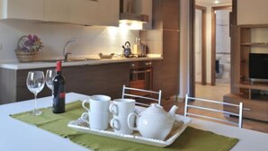 En spiseplads med et bord dækket til to personer, med en vinflaske, to glas og en bakke med hvide kopper og et te-stel.