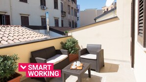 Een balkon met rieten meubilair, een plant in pot en een schotelantenne.