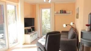A living room with a sofa, a television, a bookshelf, and a lamp.