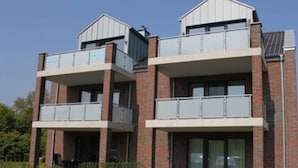 A modern two-story building with a brick facade, large windows, and balconies.