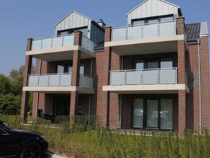 A modern two-story building with a brick facade, large windows, and balconies.
