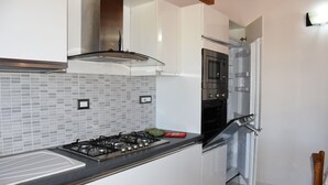 A modern kitchen with a gas stove, oven, and microwave. - SU CUILE-relax house suitable for families or groups of friends IUN P8183 (Sassari)