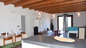 A modern kitchen with wooden beams, a dining table set for four, and a large island. - SU CUILE-relax house suitable for families or groups of friends IUN P8183 (Sassari)