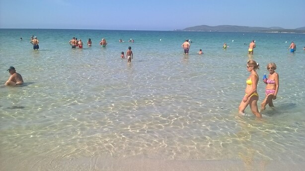 A beach with clear shallow waters and people swimming and walking. - SU CUILE-relax house suitable for families or groups of friends IUN P8183 (Sassari)