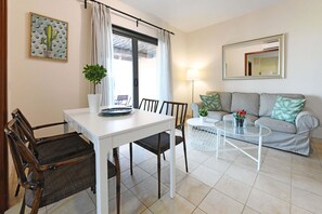 Ein Wohnzimmer mit Esstisch, Stühlen, einer Couch, einem Couchtisch und einer Topfpflanze.