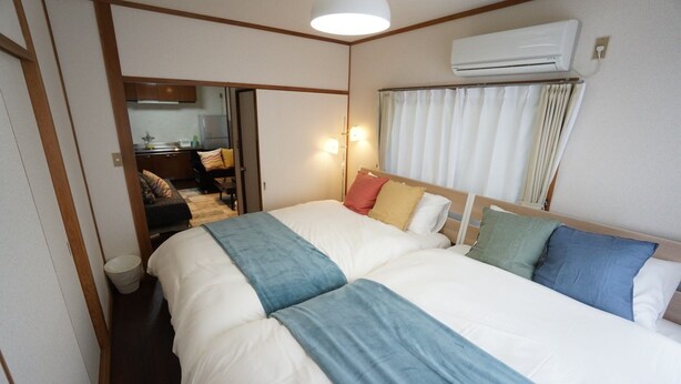 Une chambre à coucher avec un grand lit, une table de chevet, une lampe et un appareil de climatisation.
