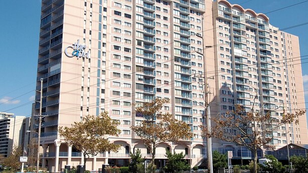 Un hotel moderno de gran altura con múltiples balcones, un letrero llamativo y un cielo despejado.