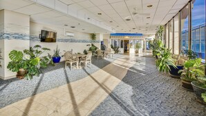 Un espacio interior amplio con techo alto, suelo de baldosas y varias plantas en macetas.