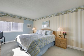 Een slaapkamer met een bed, nachtlampjes, een nachtkastje, een raam en een muur met een streepmotief.