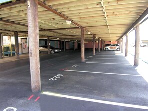 Een overdekte parkeerplaats met meerdere rijen parkeerplaatsen, gemarkeerd met witte lijnen en nummers.