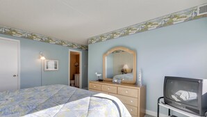 Un dormitorio con cama, cómoda, espejo y televisor.