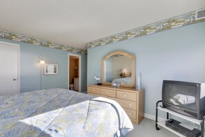 Une chambre à coucher avec un lit, une commode, un miroir et un téléviseur.