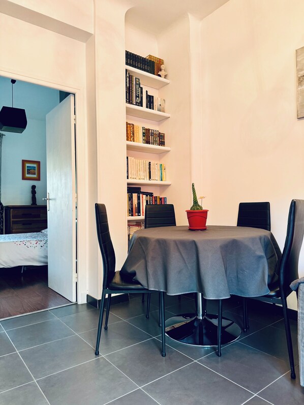 A dining area with a table, chairs, and a bookshelf.