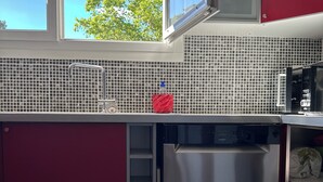 Eine moderne Küche mit Edelstahl-Kühlschrank, Mikrowelle und gefliestem Rückspritzschutz.