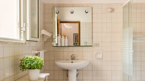 Een badkamer met een houten plafond, een wastafel, een spiegel en een douche.