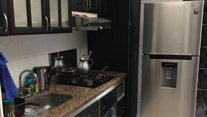 Una cucina con mobili scuri, un frigorifero in acciaio inossidabile, un fornello a gas e una macchina per il caffè.