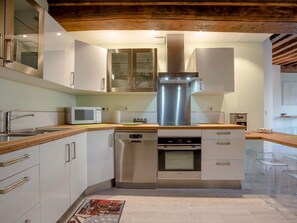 Une cuisine moderne dotée d’appareils électroménagers en acier inoxydable, de plans de travail en bois et de meubles blancs.