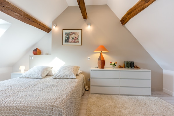 A bedroom with a bed, nightstands, a dresser, a lamp, and a picture on the wall.