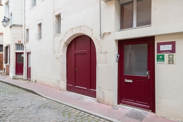 Un immeuble avec une porte rouge et une plaque indiquant qu’il s’agit d’un « Sweet Home », c’est-à-dire d’un logement offrant des commodités telles qu’une salle de sport et une piscine.