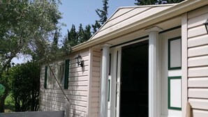 Une maison de plain-pied avec un porche à l’avant, une porte-fenêtre coulissante et un petit espace porche agrémenté d’un banc.