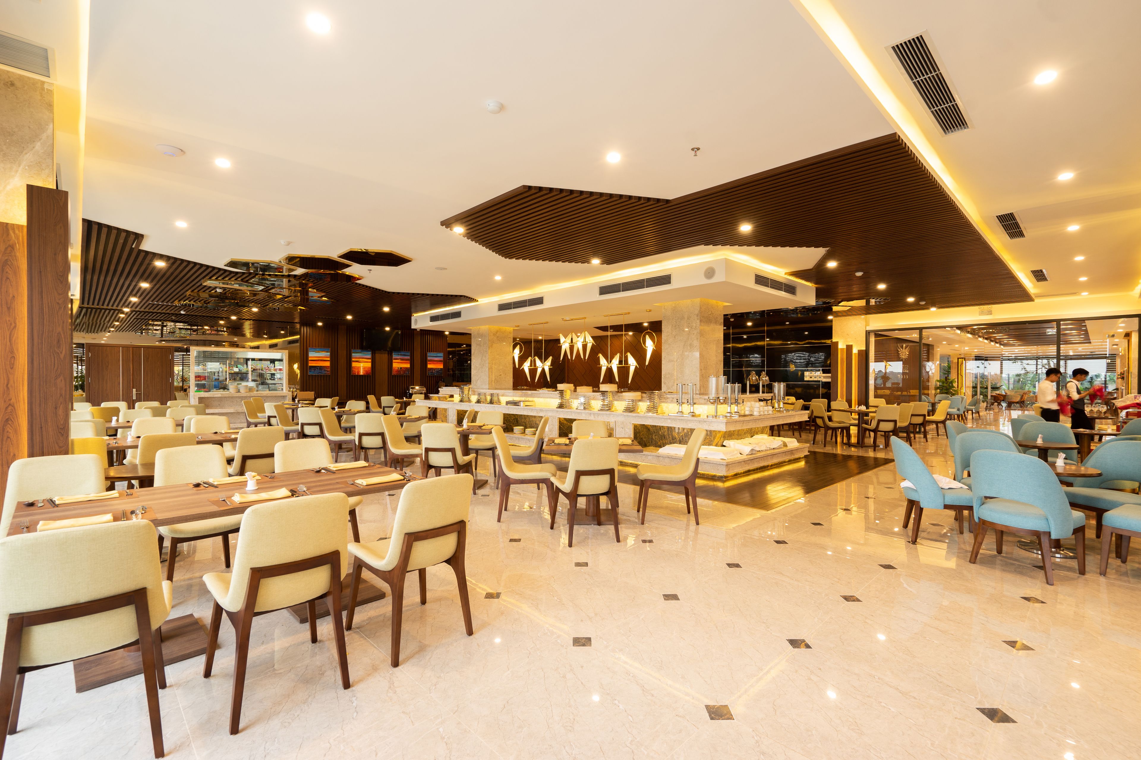 A spacious hotel lobby with multiple seating areas, a central bar, and a modern ceiling design.